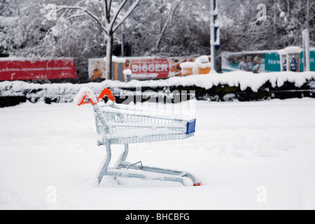 Ein verlassener Einkaufswagen verließ auf einem Supermarkt-Parkplatz nach starkem Schneefall. Stockfoto