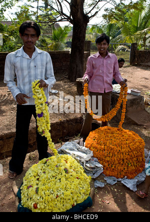 Männer verkaufen Girlanden in Größen abgeholt Bedarf von kontinuierlich Gewinde haufenweise frisch gelb und orange Ringelblumen. Stockfoto