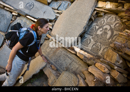 Christine Kolisch untersucht eine tibetische buddhistische MANI Stein von MILAREPA in NUPRI Bereich - um MANASLU Trekking, NEPAL Stockfoto