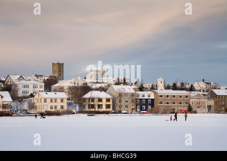 Menschen zu Fuß auf zugefrorenen See Tjörnin. Die Innenstadt von Reykjavik Island Stockfoto