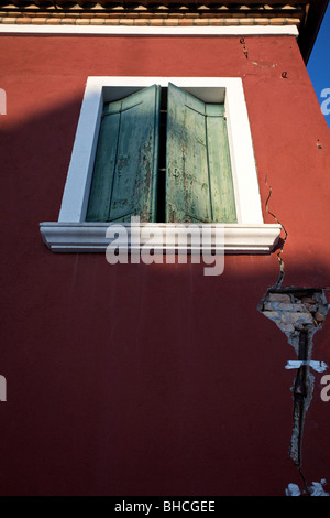 Typische italienische Fenster mit grünen Fensterläden auf einem roten Gebäude, Burano, Venedig. Stockfoto