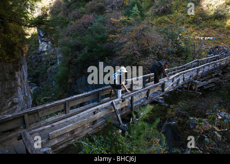 Bodhi Garrett und Christine Kolisch überqueren Sie eine Brücke mit einem 1000 Fuß Drop-off - um MANASLU Trekking, NEPAL Stockfoto