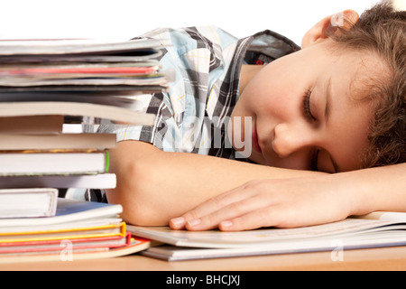 Porträt von Schuljunge schlafen auf seinem Schreibtisch in der Nähe von einem Stapel Bücher Stockfoto