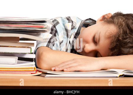 Porträt von Schuljunge schlafen auf seinem Schreibtisch in der Nähe von einem Stapel Bücher Stockfoto