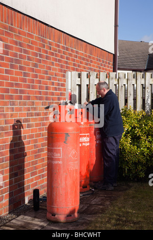 UK, Europa. Arbeiter eine inländischen Calor Gasflasche vor einem Haus ändern Stockfoto