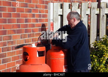 Arbeiter eine inländischen Calor Gasflasche vor einem Haus ändern Stockfoto