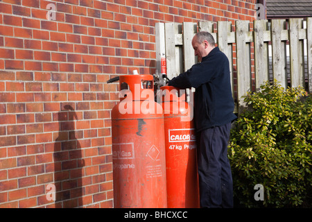 UK, Europa. Arbeiter eine inländischen Calor Gasflasche vor einem Haus ändern Stockfoto