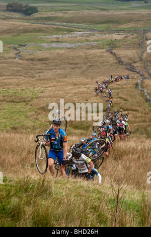 Masse der Radfahrer tragen ihre Fahrräder auf einem Berg während der drei Zinnen Cyclo-Cross in Yorkshire, Vereinigtes Königreich Stockfoto