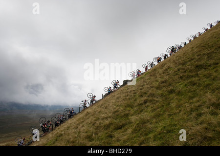 Masse der Radfahrer tragen ihre Fahrräder auf einem Berg während der drei Zinnen Cyclo-Cross in Yorkshire, Vereinigtes Königreich Stockfoto