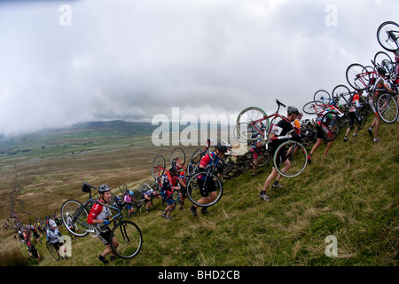 Masse der Radfahrer tragen ihre Fahrräder auf einem Berg während der drei Zinnen Cyclo-Cross in Yorkshire, Vereinigtes Königreich Stockfoto