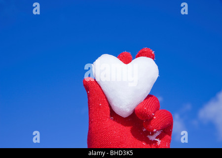 Red behandschuhte Hand, die Herzen der Schnee Stockfoto