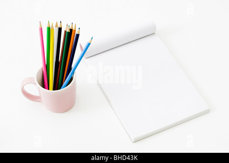 Buntstifte in Tasse weiter auf leere Notepad Stockfoto