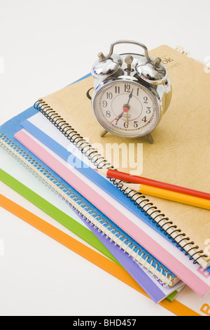 Stapel von Notebooks mit Bleistifte und Wecker Stockfoto