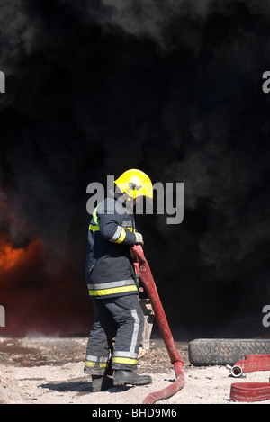 Einrichten von Boden-Monitor gegen dicke schwarze Rauchfahne Feuerwehrmann Stockfoto