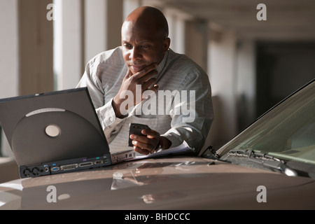 Afrikanischen Geschäftsmann mit Laptop auf Motorhaube Stockfoto