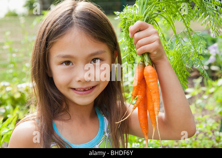 Gemischte Rassen Mädchen halten Karotten Stockfoto