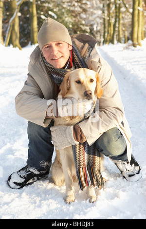 Man Walking Hund durch den verschneiten Wald Stockfoto