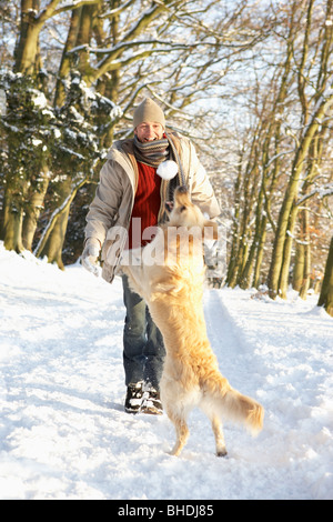 Man Walking Hund durch den verschneiten Wald Stockfoto