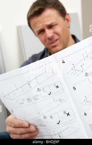 Verwirrten Mann liest Montageanleitung für Flachgehäuse Möbel Stockfoto