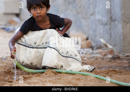 Indische Mädchen spielen mit einem Wasserschlauch Stockfoto