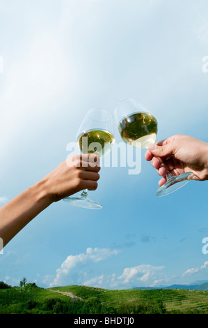 Junge Frau und junger Mann Hände halten Weingläser mit Weißwein und Toasten Stockfoto