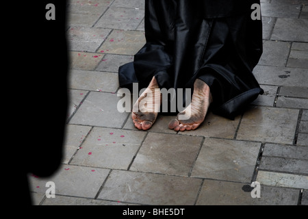 Die barfüssige Heilige Woche Teilnehmer kniet auf der Straße während der Osterferien Prozession in Málaga, Spanien. Stockfoto