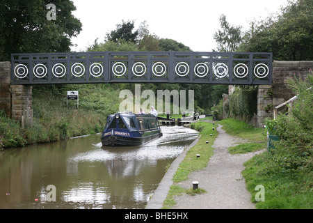 Ein Kanal Barge oder schmalen Boot auf der Macclesfield Kanal gehen unter einer Brücke nur nach dem coming out eines Schlosses. Stockfoto