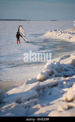 Eine Frau Skifahren auf Eisschollen im Winter mit einem Kitewing an Ostsee, der Bottnische Meerbusen, Finnland Stockfoto