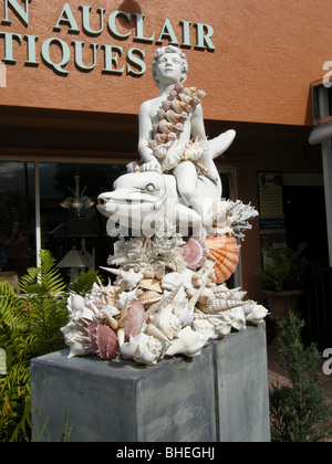 Junge auf einem Delphin Schale Skulptur außerhalb ein Antiquitätengeschäft auf Fifth Ave South Naples Florida USA Stockfoto