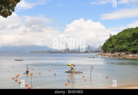 Rettungsschwimmer, sitzen auf einer schwimmenden Plattform, Lamma Kraftwerk im Hintergrund, Lo So Shing Beach, Lamma Island, Hongkong Stockfoto