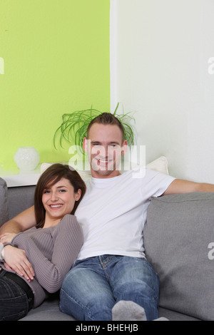 Junge, glückliche Paar zu Hause entspannen. Es sitzt bequem auf dem sofa Stockfoto