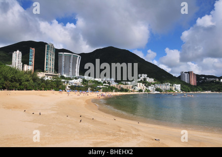 Blick auf den belebten Strand, geschwungene ostwärts eine Berg-Silhouette hinter Luxus Wohnungen, Repulse Bay, Hong Kong Stockfoto