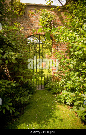 Schmiedeeisernes Tor in einer Mauer, das zu einem geheimen Garten führt Stockfoto