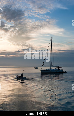 Kleines Boot mit einem Mann schwimmt von einer Yacht an einem warmen Sommern Morgen Stockfoto