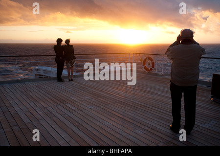 Junges Paar, den Sonnenuntergang, Passagier auf dem Achterdeck, fotografieren, Kreuzfahrtschiff, Queen Mary 2, Transatlantic, Atla Stockfoto