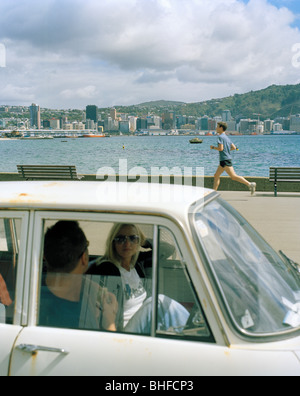 Ein paar in ein Auto und ein Jogger auf der Promenade, Oriental Parade, Wellington, Nordinsel, Neuseeland Stockfoto