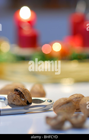 Nussknacker und Walnüsse mit Adventskranz mit brennenden Kerze im Hintergrund Stockfoto