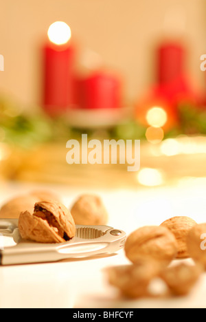 Nussknacker und Walnüsse mit Adventskranz mit brennenden Kerze im Hintergrund Stockfoto