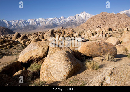 Vie an einen amerikanischen Schulbus in eine felsige Wüste vor schneebedeckten Bergen, Alabama Hills, Lonepine, Kalifornien, USA Stockfoto