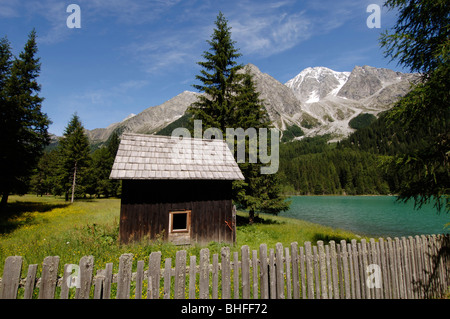 Kabine und Holzzaun am Antholzer See in einer idyllischen Berglandschaft im Sonnenlicht, Val Pusteria, Südtirol, Italien, Euro Stockfoto