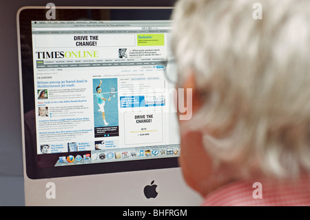 Älterer Herr, der The Times Zeitung Online-Ausgabe auf einem Desktopcomputer von Apple. Stockfoto