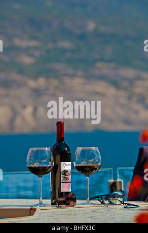 Rotwein in Weingläsern und Flasche Wein auf einer Terrasse Tisch mit Blick auf Okanagan Lake von Bonitas Weingut, Summerland, Okanagan Stockfoto