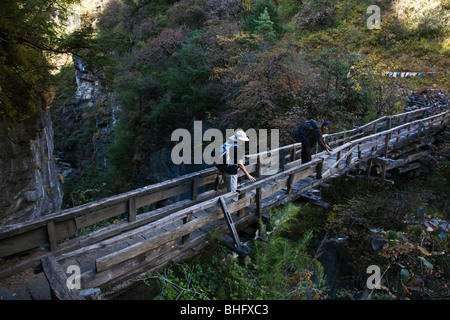 Bodhi Garrett und Christine Kolisch überqueren eine wackelige Brücke mit eine 100 Fuß-Drop off auf beiden Seiten - MANASLU Trekking, NEPAL Stockfoto