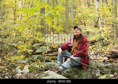 Ein Mann sitzt auf einem Felsen im Wald Stockfoto