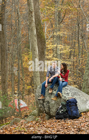 Junges Paar sitzt auf Fels im Wald Stockfoto