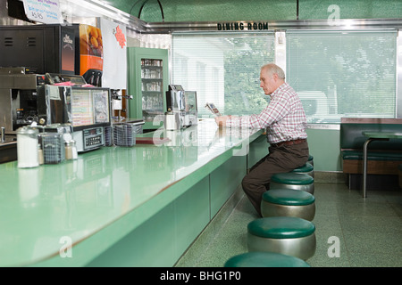 Alter Mann in einem Diner lesen Stockfoto