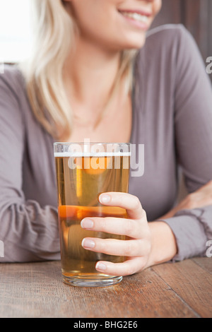 Junge Frau in bar halten Pint Bier Stockfoto