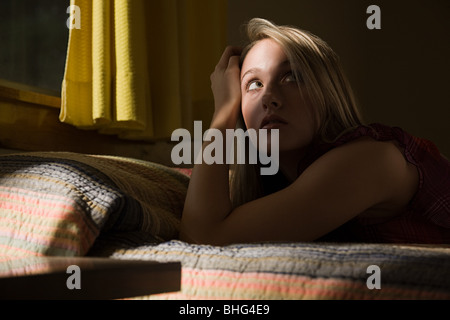 Junge Frau im Bett im Schatten Stockfoto