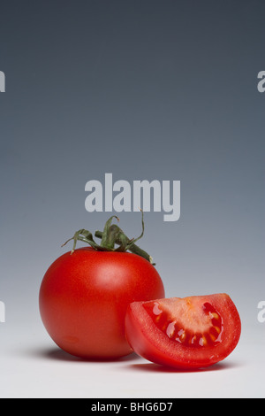 Tomaten ganze und geschnittene auf einem einfarbigen Hintergrund Stockfoto