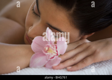 Junge Frau auf Massagetisch mit Orchideenblüten Stockfoto